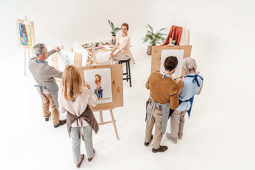 high angle view of senior people painting on easels during art class