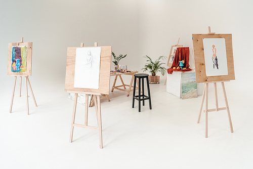 easels with paintings in empty art studio