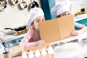 adorable children in chef hats holding cookbook and 