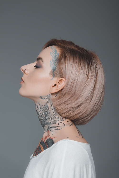 profile portrait of beautiful tattooed girl with closed eyes isolated on grey