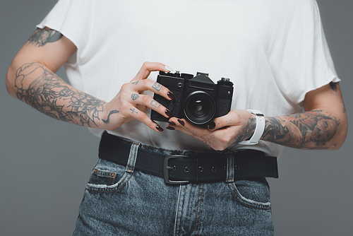 mid section of girl with tattoos holding camera isolated on grey
