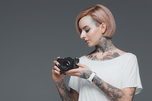 beautiful girl with tattoos holding camera isolated on grey