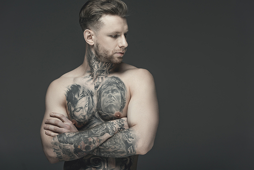shirtless tattooed man with crossed arms, isolated on grey