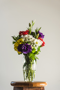 bouquet of colorful flowers in glass vase, isolated on grey