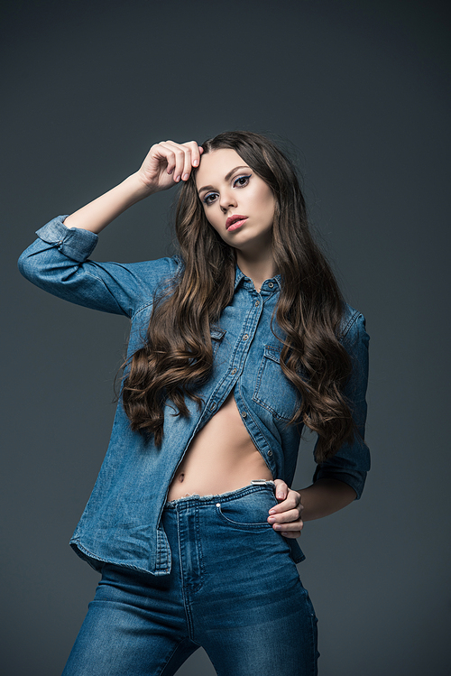 beautiful stylish girl with long hair posing in jeans, isolated on grey