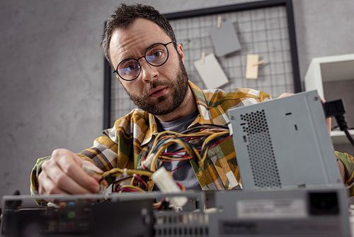 repairman in glasses repairing broken computer