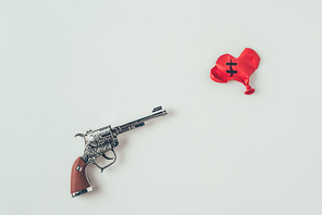 top view of gun barrel aiming at repaired heart shaped balloon isolated on white