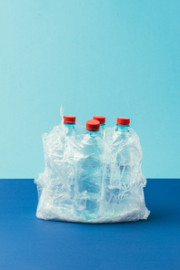 close up view of plastic bottles in plastic bag on blue background, recycle concept