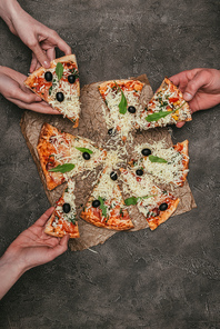 Close-up view of people eating pizza on dark background