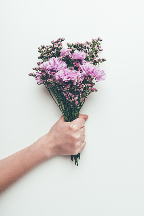 cropped shot of person holding beautiful elegant bouquet of tender flowers isolated on grey