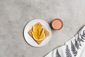 sandwich with honey and orange slices and glass of fresh juice on grey