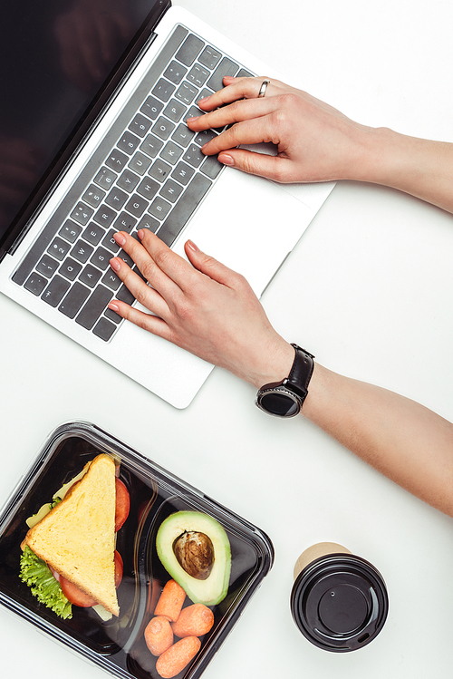 cropped image of woman using laptop at table with food in lunch box isolated on white