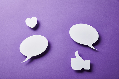 white speech bubbles, thumbs up card and small paper heart on purple surface