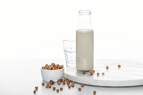 chickpea milk in bottle near chickpea in bowl and empty glass isolated on white