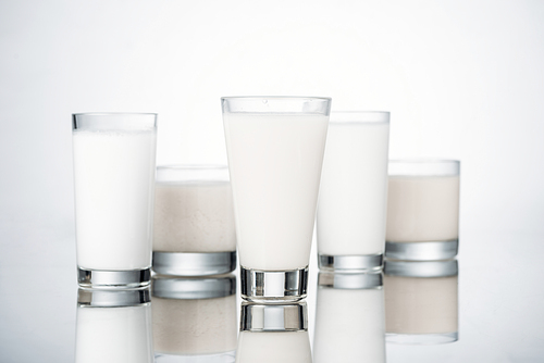 glasses with fresh alternative milk on grey background with reflection