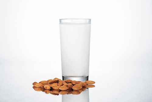 almond vegan milk in glass nuts on grey background