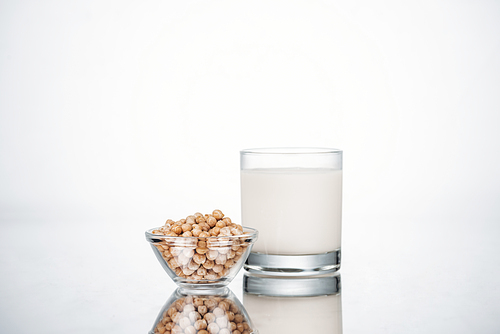 chickpea vegan milk in glass near bowl with beans on grey background