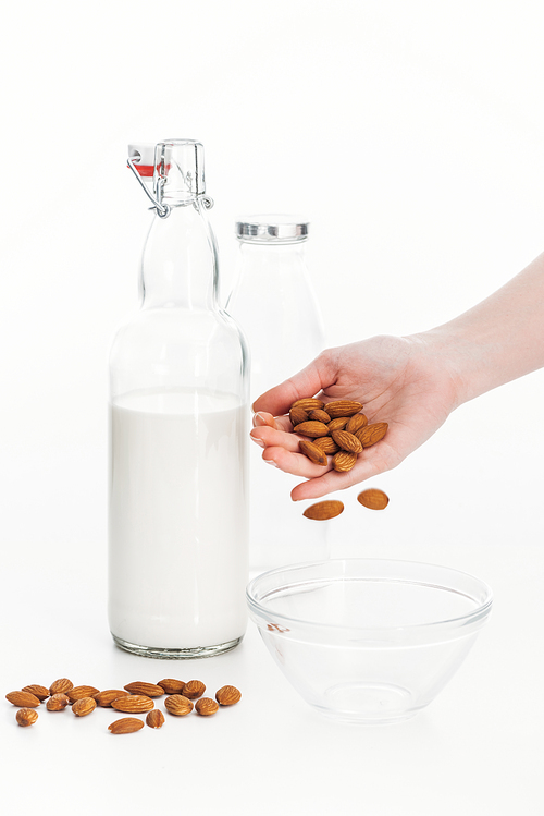 cropped view of woman putting almonds in bowl while cooking almond vegan milk