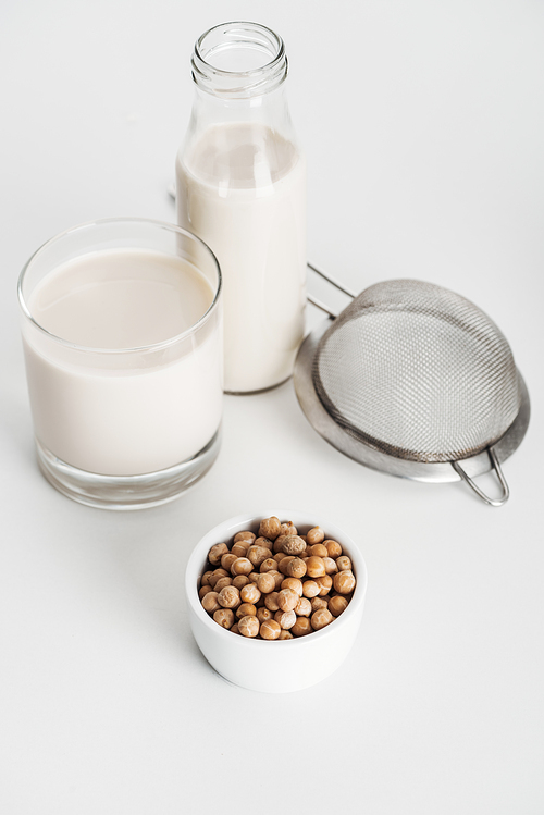 chickpea in bowl near vegan chickpea milk and sieve on grey background
