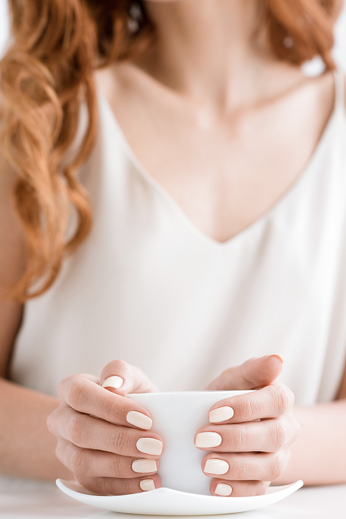 cropped shot of woman holding cup of coffee on table