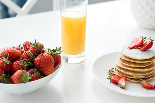 close-up shot of tasty pancakes with strawberries and orange juice