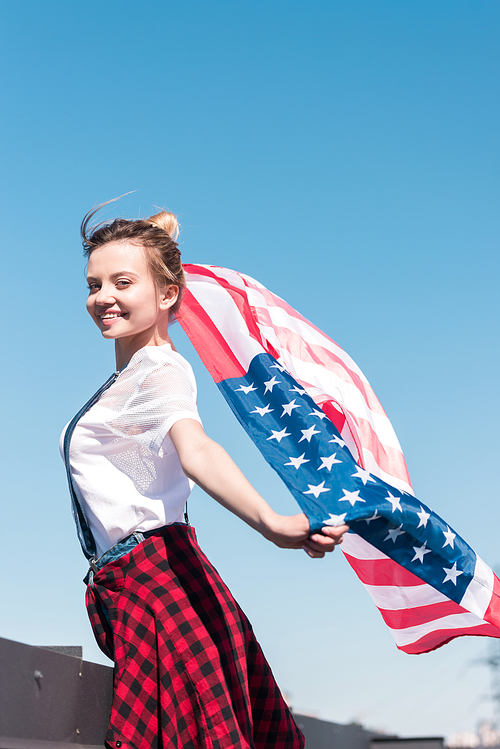young woman holding american flag against blue sky, 독립기념일 concept