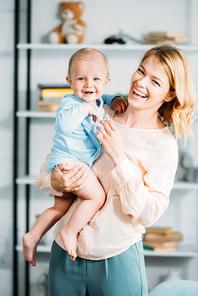 laughing mother carrying her little child and  at home