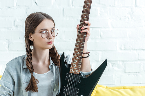 beautiful teen girl sitting on sofa with electric guitar