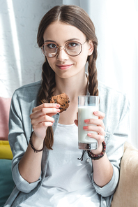 beautiful teen girl with cookie and milk in glass