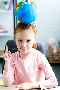 beautiful schoolgirl with globe on head  and pointing up with finger