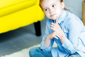 cropped shot of pensive little child looking away at home