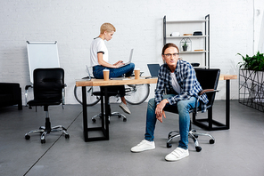 young woman using laptop and male colleague  in office