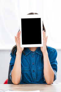 young woman covering face by digital tablet with blank screen