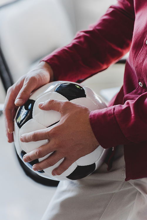 cropped shot of businessman holding soccer ball in office