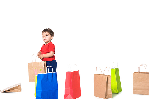 cute boy playing with shopping bags isolated on white .