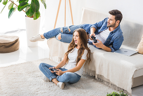 excited young woman playing video game with boyfriend at home