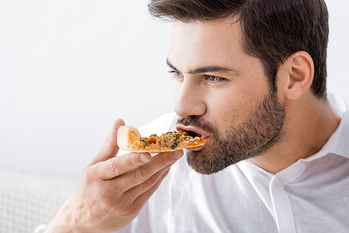 portrait of young man eating pizza alone at home