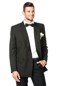 smiling groom buttoning suit and looking away isolated on white