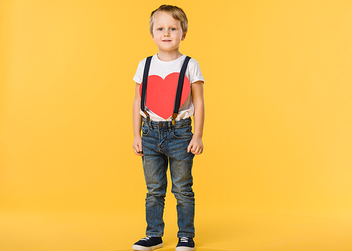 adorable little boy with red paper heart isolated on yellow, st valentines day concept