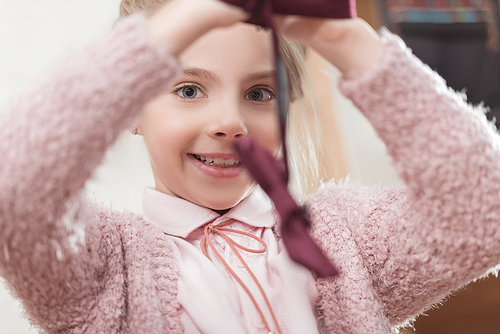 happy kid holding bow tie in hands while  at shop