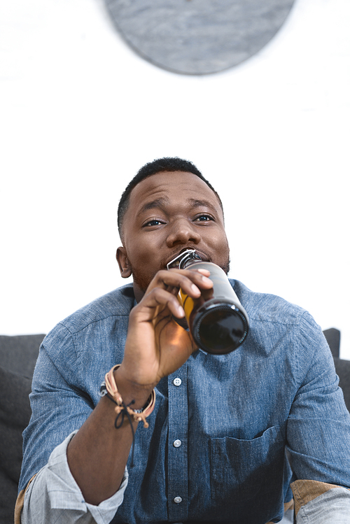 Young african american man drinking beer from bottle