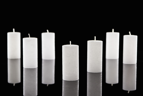 selective focus of white candles with reflection isolated on black