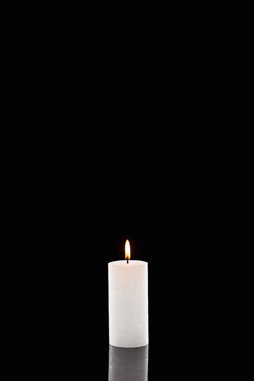 burning white candle glowing isolated on black