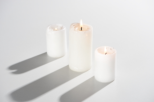 burning candles glowing on white background with shadow