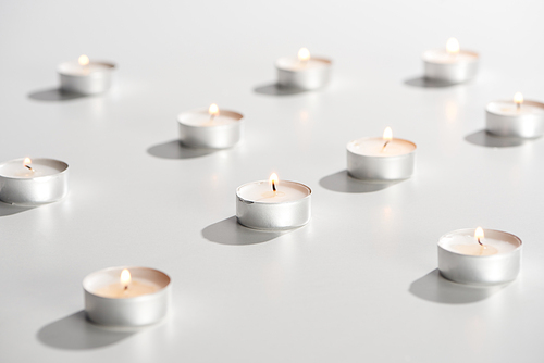 selective focus of burning candles glowing on white surface