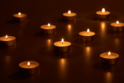 selective focus of burning white candles glowing in dark