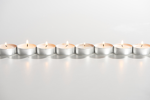 burning candles glowing in line on white background