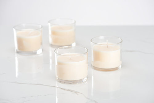 selective focus of white candles in glass on marble white surface