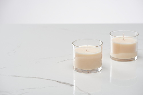 white candles in glass on marble white surface