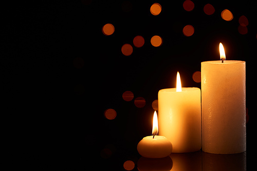 burning candles glowing in dark with bokeh lights on background